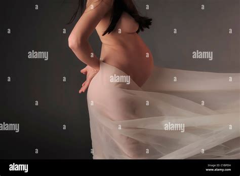 Naked Pregnant Woman With Long Dark Hair Poses With Flowing White Fabric Featuring Her