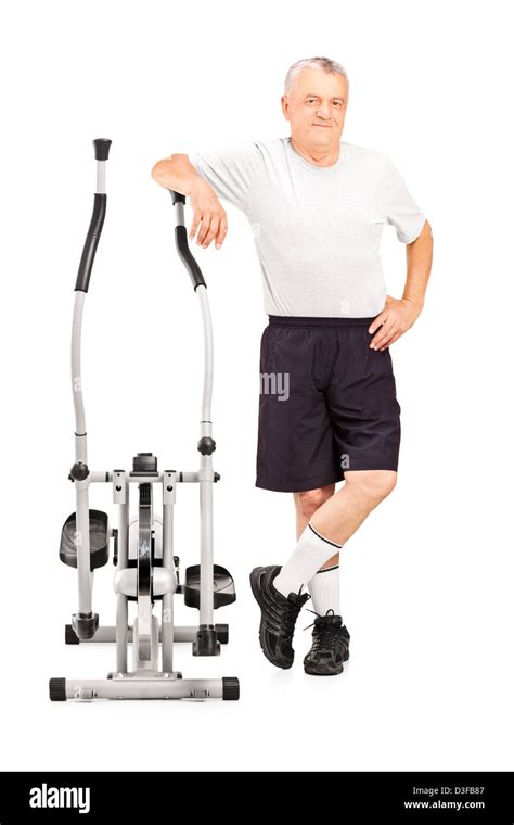 Full Length Portrait Of A Mature Athlete Standing Next To A Cross Trainer Machine Isolated On