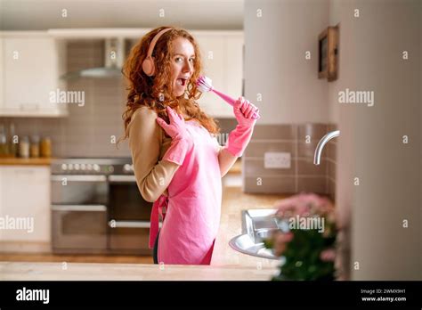 Redhead Woman Washing Dishes In The Kitchen And Listening To Music By