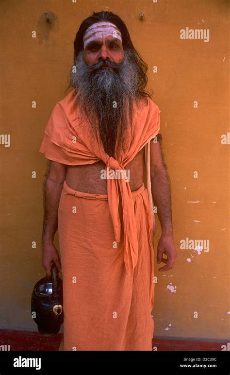 Indian Sadhu Priest Wearing Saffron Clothes Near River Ganges In Oldest