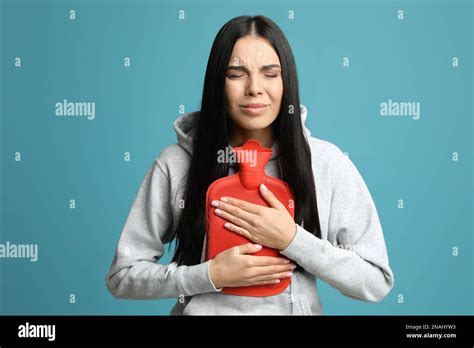 Woman Using Hot Water Bottle To Relieve Pain On Light Blue Background Stock Photo Alamy