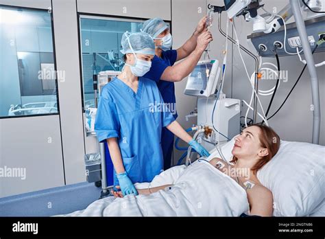 Intensive Care Patient Nurses Attending To Female Patient In Intensive Care Unit Of Hospital