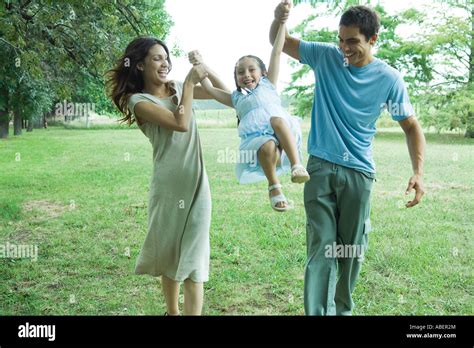 Family outdoors, parents swinging girl Stock Photo - Alamy