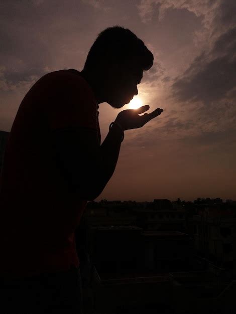 Ilusión óptica de la silueta de un hombre besando el sol durante la