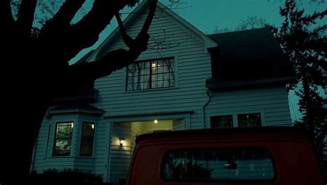 A Red Truck Parked In Front Of A White House At Night With The Lights On