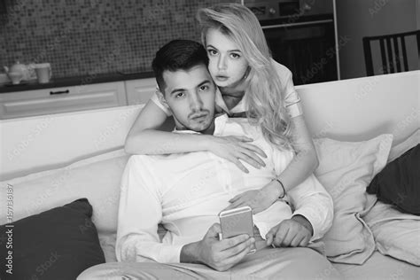 Handsome Brunette Man Sitting At Sofa And Using Smartphone Pretty Beautiful Caucasian Girl With