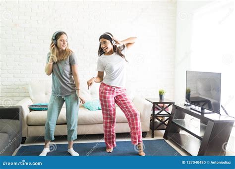 Female Friends Dancing While Listening To Music On Headphones Stock