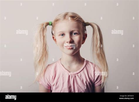Closeup Portrait Of Cute Smiling Blonde Caucasian Preschool Girl In Pink T Shirt On Light