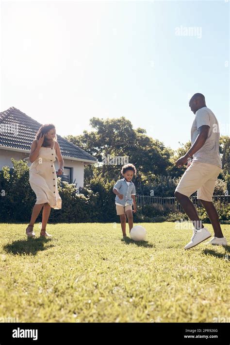 Familia de raza mixta feliz jugando al fútbol fuera en el jardín en