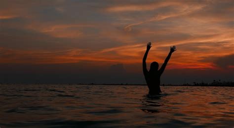 Silhueta De Mujer Con Los Brazos Levantados Nadando En El Mar Contra El