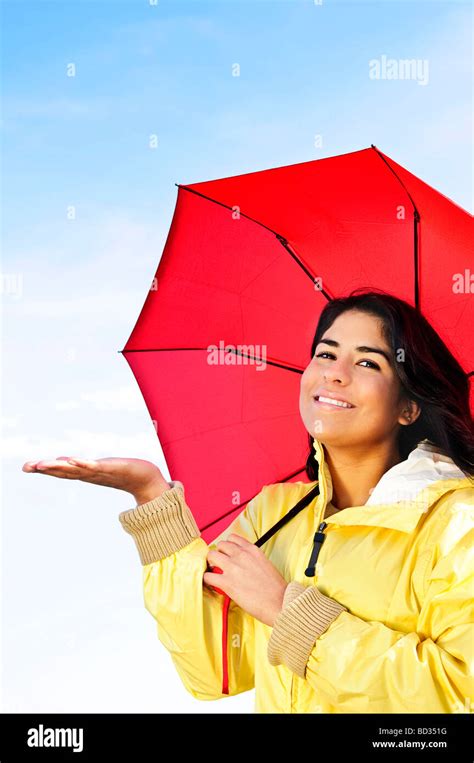 Portrait Of Beautiful Smiling Girl Wearing Yellow Raincoat Holding Red