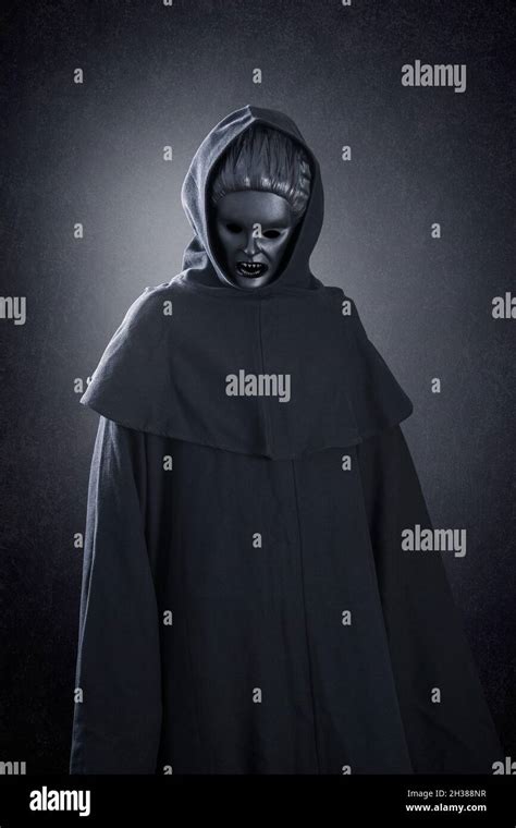 Woman ghost in hooded cloak over dark misty background Stock Photo - Alamy