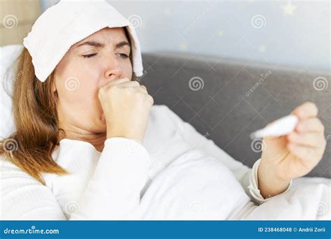 Sick Woman With Thermometer Lying In Bed With Cold And High Fever A