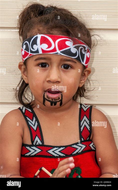 A Maori child dressed in her traditional dance dress watching her ...