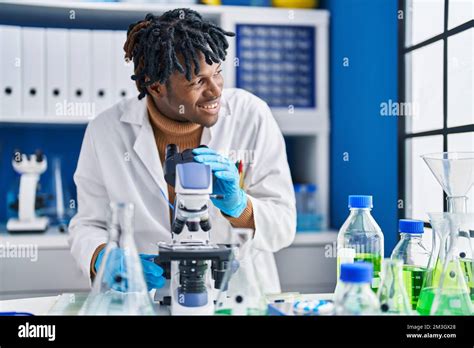 African American Man Scientist Using Microscope At Laboratory Stock