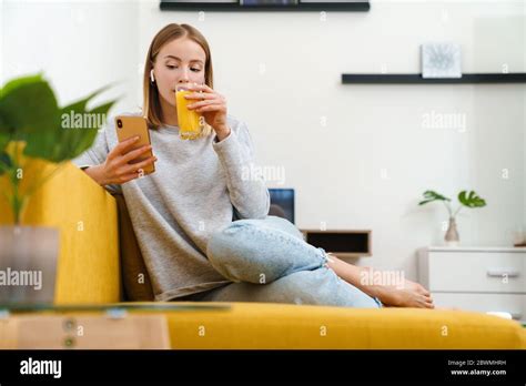 Belle jeune femme blonde portant des vêtements décontractés reposant sur un canapé à la maison