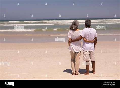 Senior Couple Standing On A Beach With Their Arms Around Each Other