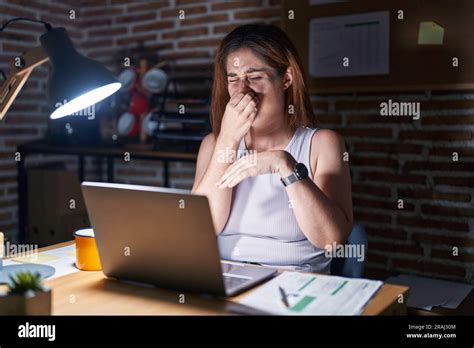 Brunette Woman Working At The Office At Night Smelling Something Stinky And Disgusting