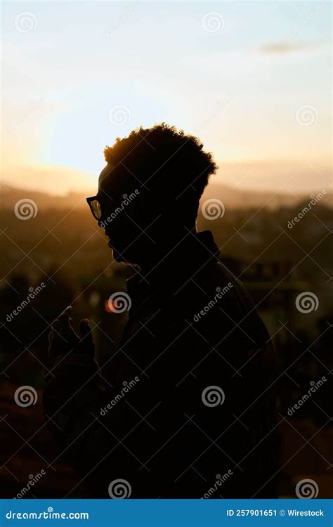 Toma Vertical De Una Silueta De Un Hombre Mirando La Puesta De Sol