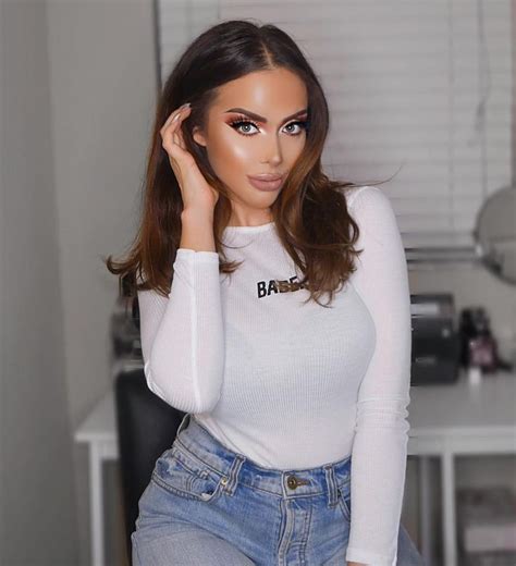 A Woman In White Shirt And Jeans Posing For The Camera With Her Hand On