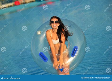 A Woman in a White Bathing Suit with an Inflatable Circle in a Water ...