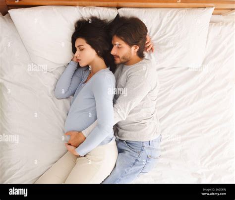 Loving Husband Hugging His Pregnant Wife While They Sleeping In Bed