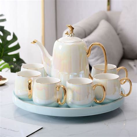 A Tea Set Is Sitting On A Tray With Cups And Saucers In Front Of It