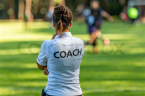 Back View Of A Female Sport Coach Watching Her Team Compete At An