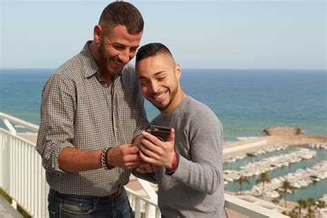 Retrato de una feliz pareja gay al aire libre revisando su teléfono móvil Foto Premium