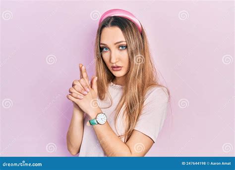 Young Blonde Girl Wearing Casual Clothes Holding Symbolic Gun With Hand