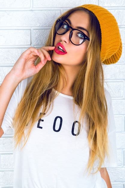 Junge hübsche blonde frau mit hellen sexy lippen brille und hut tragend Kostenlose Foto