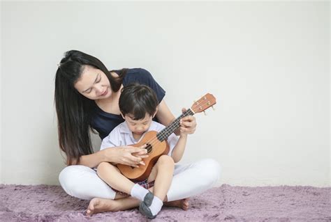 Premium Photo Asian Mother Teach Her Son To Play Ukulele On Carpet