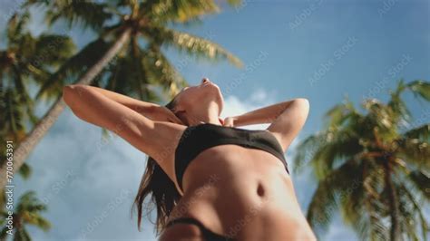 Vidéo Stock A woman wearing a bikini is standing confidently in front of a row of tall palm