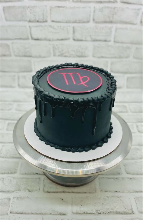 a black cake sitting on top of a metal plate next to a brick wall with the word it