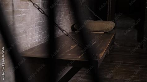 A Close Up Of A Wooden Bed Hanging On Chains A Shelf With A Pillow In An Old Prison Cell A