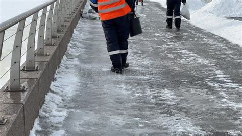 Workers Spreading Salt To Slipper Sidewalk Winter Road Treatment With