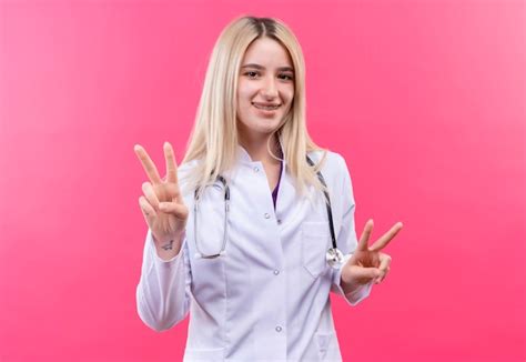 Souriant médecin jeune fille blonde portant un stéthoscope en robe médicale et orthèse dentaire