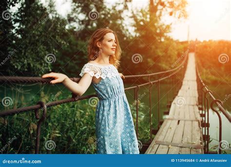 Young Beautiful Girl Standing On The Bridge Over The River Stock Photo