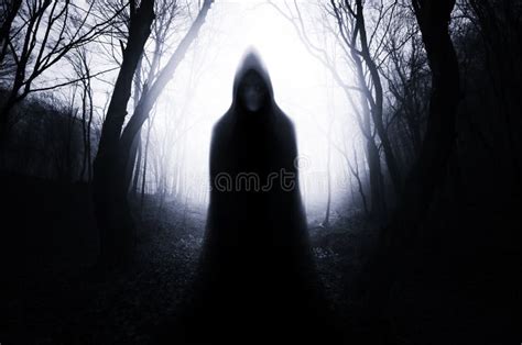 Hooded Ghost In Haunted Forest With Fog On Halloween Night Stock Photo