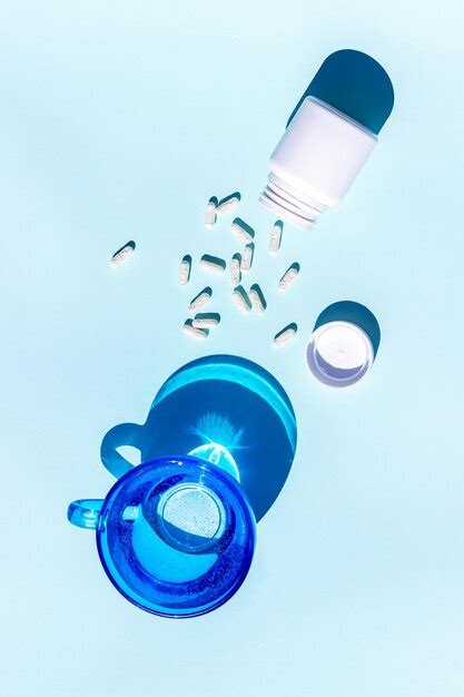 Píldoras y vaso de agua sobre fondo azul medicina concepto de salud