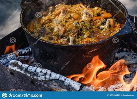 Pilau Que Cozinha A Caldeira Da Fogueira Do Jogador Lenha Da Fogueira