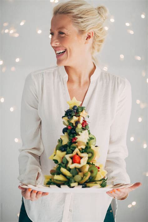 Happy Blonde Woman Holding A Christmas Tree Made Of Fruit By Stocksy Contributor Lumina