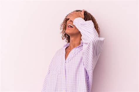 Joven mujer transexual latina aislada sobre fondo rosa se ríe con alegría manteniendo las manos