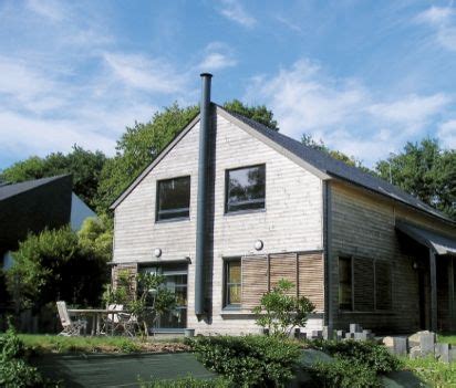 The House Is Made Out Of Wood And Has A Large Front Yard With Green Plants