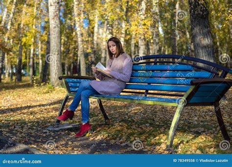 A Menina Senta Se Em Um Banco De Parque E Em Guardar Um Livro Foto De