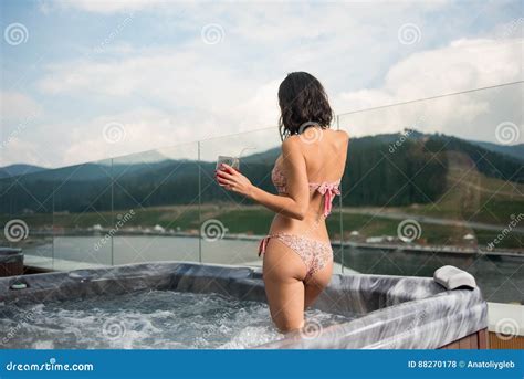 Back View Brunette Girl In Bikini Standing With Cocktail At The Jacuzzi Outdoors On Vacation