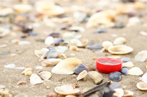 Premium Photo | Red bottle caps discarded beach mixed with shells