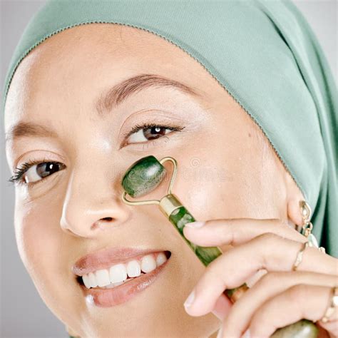 Muslim Woman Smiling And Using A Facial Roller On Her Skin Beauty