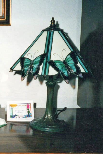 A Green Lamp Sitting On Top Of A Wooden Table Next To A Framed Picture And An Open Book