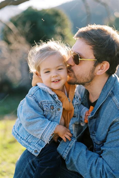 Premium Photo Dad Kisses On The Cheek A Little Smiling Girl On His
